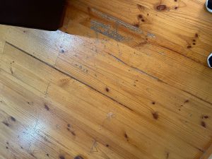 Close up of failed coating and grey worn timber on radiata pine floorboards